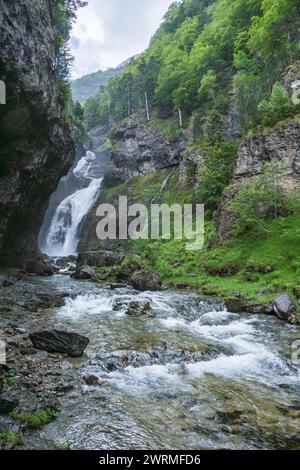Les eaux se précipitent dans une gorge verdoyante, avec une cascade majestueuse comme toile de fond au cœur de la vallée d'Ordesa, Huesca Banque D'Images