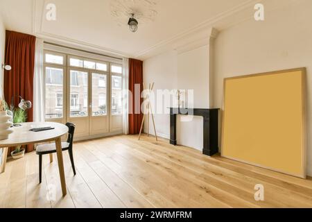 Un salon spacieux doté de grandes fenêtres avec des rideaux rouges, une cheminée décorative et un mobilier minimaliste sur du parquet. Banque D'Images