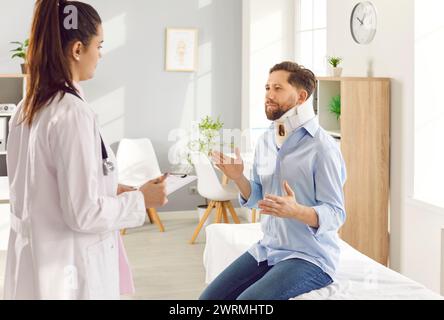 Homme blessé après un accident en attelle de cou assis sur le canapé dans la clinique et parlant au médecin. Banque D'Images