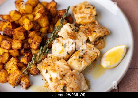 Morue frite dans une sauce à la crème d'orange avec thym et pommes de terre croustillantes au four. Cuisine domestique. Mise au point sélective, gros plan. Banque D'Images