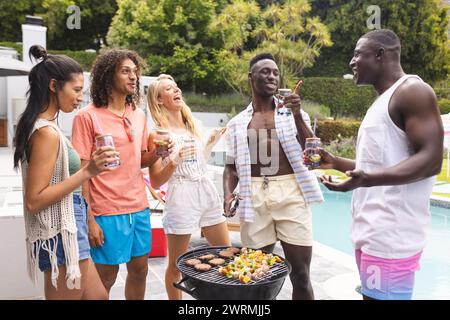 Groupe diversifié d'amis profitant d'un barbecue au bord de la piscine Banque D'Images