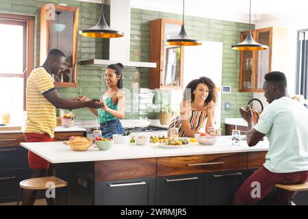 Groupe diversifié profite d'un moment animé dans une cuisine moderne Banque D'Images