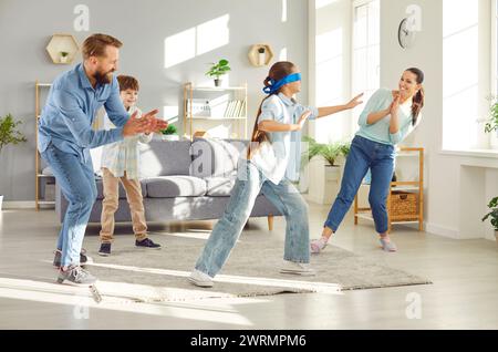 Fille enfant bandée attrapant sa famille jouant à cache-cache à la maison ensemble. Banque D'Images