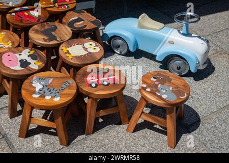 Tabourets en bois peints à la main pour les enfants et une voiture à pédales vintage au marché hebdomadaire de la station de ski populaire, Chamonix, haute Savoie, France Banque D'Images