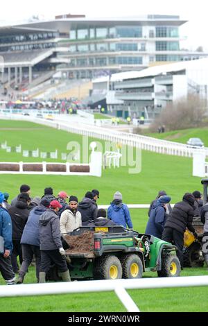 Hippodrome de Cheltenham, Gloucestershire Royaume-Uni - mercredi 13 mars 2024 - le personnel au sol vérifie la surface du gazon de l'hippodrome et comble les trous dans l'herbe avant le début du deuxième jour du Festival de Cheltenham de cette année. Photo Steven May / Alamy Live News Banque D'Images