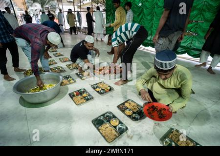 Des bénévoles distribuent et organisent des rangées de repas 'iftar' pour les dévots afin de rompre leur jeûne, pendant le mois sacré du Ramadan, à Burha Jame Masjid, le 13 mars 2024 à Guwahati, Assam, Inde. Crédit : David Talukdar/Alamy Live News Banque D'Images