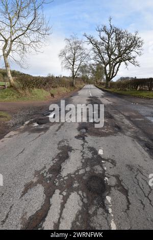 Un hiver humide a fait des ravages sur les routes écossaises. Ici, une série de nids de poule sur la B9127 à Inverarity a endommagé la suspension et les pneus du véhicule. Banque D'Images