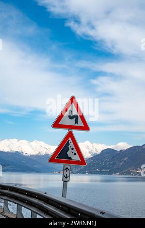 Voiture de conduite sur la route le long des rives du lac de Côme dans le nord de l'Italie, des journées ensoleillées printanières, des vues sur les montagnes alpines, l'eau et les villages Banque D'Images