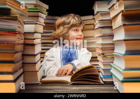 Portrait de beau petit enfant ukrainien avec livre dans la bibliothèque. Garçon d'école primaire posant dans une librairie ou une librairie. Banque D'Images