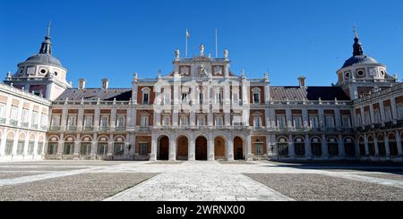 Le Palais Royal d'Aranjuez avec une cour en pierre spacieuse et une tour de l'horloge proéminente au loin Banque D'Images