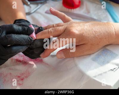 Manucure femme à l'aide d'une éponge de polissage après avoir enlevé le vieux vernis pour la peinture permanente des ongles Banque D'Images