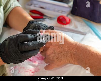 Manucure femme à l'aide d'une éponge de polissage après avoir enlevé le vieux vernis pour la peinture permanente des ongles Banque D'Images