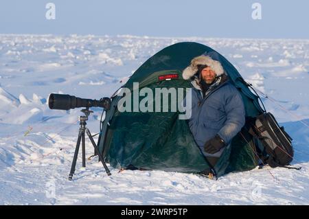 Le photographe Steven Kazlowski avec trépied d'appareil photo et tente Hilleberg campait le long de la côte arctique dans la région du printemps 1002 de l'ANWR Alaska Banque D'Images