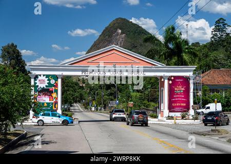 Entrée de la porte impériale de la ville Petropolis sur l'avenue Ayrton Senna tandis que la circulation passe sous elle sous l'après-midi d'été ensoleillé ciel bleu nuageux. Banque D'Images