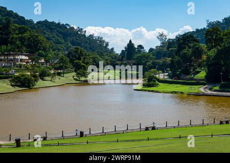 Le grand lac Quitandinha entouré de champs d'herbe verte et de forêt dense dans le district de Quitantinha sous l'après-midi d'été ensoleillé ciel bleu nuageux. Banque D'Images