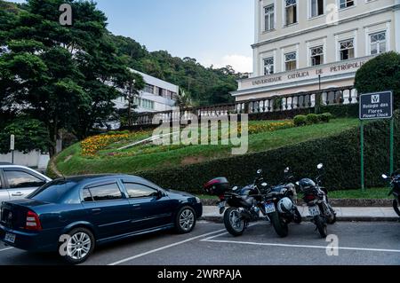 Véhicules garés dans les places de stationnement devant l'horloge à fleurs à l'Université catholique de Petropolis dans le district Centro pendant l'après-midi d'été. Banque D'Images