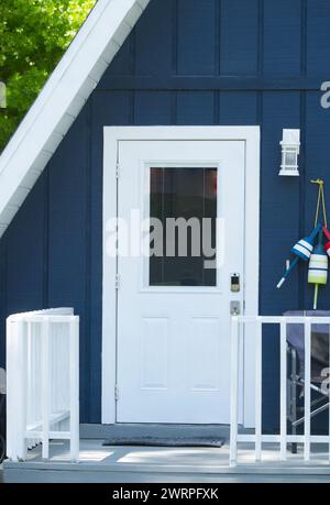 Gros plan de mignon Adorable Une maison en forme de triangle de cadre ou une maison avec la couleur bleu foncé avec porte blanche, garde-corps de porche en bois, décor de thème nautique Banque D'Images