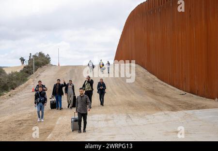 Campo, États-Unis. 13 mars 2024. Les migrants marchent le long du côté américain du mur frontalier avec le Mexique pour se rendre à la patrouille frontalière américaine près de Campo, en Californie, le 13 mars 2024. Un projet de loi bipartisan sur l'immigration sénatoriale visant à régler la question de l'immigration migrante est bloqué à la Chambre en raison de la politique de l'année électorale. Photo de Pat Benic/UPI crédit : UPI/Alamy Live News Banque D'Images