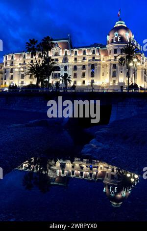 © Francois Glories/MAXPPP - 13/03/2024 heure Bleu sur l'Hôtel Negresco, Promenade des Anglais, avec son reflet dans une flaque d'eau de mer sur la plage de galets. Crédit : MAXPPP/Alamy Live News Banque D'Images