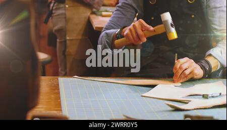 Image d'une lumière incandescente au-dessus d'un homme caucasien travaillant dans un atelier Banque D'Images