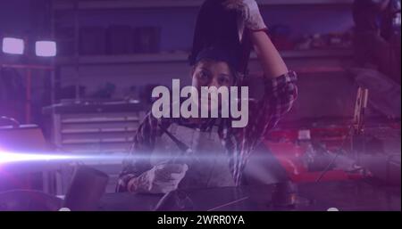 Image de lumière incandescente au-dessus d'une femme caucasienne travaillant dans un atelier Banque D'Images