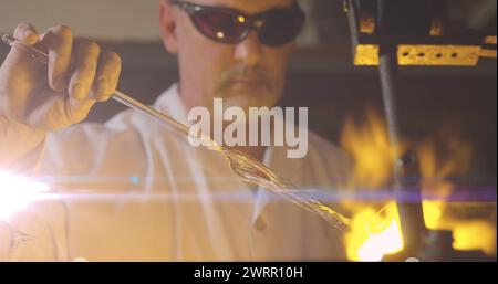 Image d'une lumière incandescente au-dessus d'un homme caucasien travaillant dans un atelier Banque D'Images