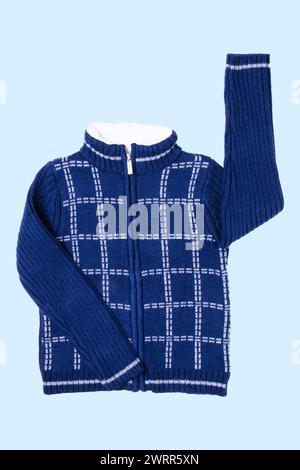 Veste d'automne et d'hiver. Un cardigan tricoté en laine bleu foncé ou un pull avec un motif à carreaux blanc sur fond bleu clair. Saut chaud confortable pour enfants Banque D'Images