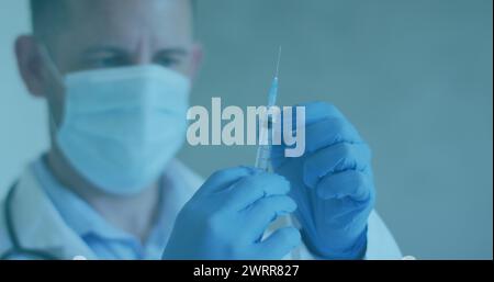 Image de cellules covid 19 et médecin masculin portant un masque préparant une seringue de vaccin Banque D'Images