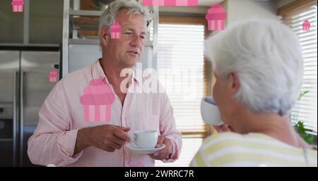 Image de gâteaux de fées roses sur un couple âgé caucasien heureux parlant et buvant du thé Banque D'Images