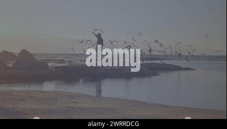Spot lumineux de lumière contre afro-américain jouissant sur les rochers près de la mer Banque D'Images