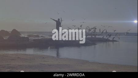 Spot lumineux de lumière contre afro-américain jouissant sur les rochers près de la mer Banque D'Images