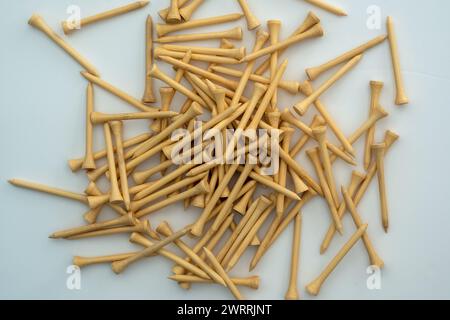 Un petit tas de tees de golf en bambou couleur bois naturel sur une surface blanche Banque D'Images