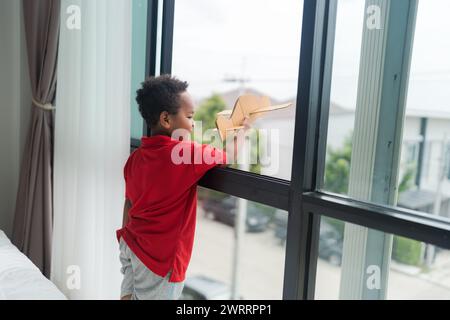 Un petit garçon imagine être un pilote jouant avec des avions jouets à la maison sur le sol dans sa chambre. Banque D'Images