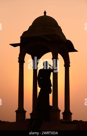 Silhouette de Subhas Chandra Bose statue sous la canopée derrière le monument commémoratif de guerre de la porte de l'Inde dans un coucher de soleil glorieux, statue monolithique Netaji en granit noir Banque D'Images