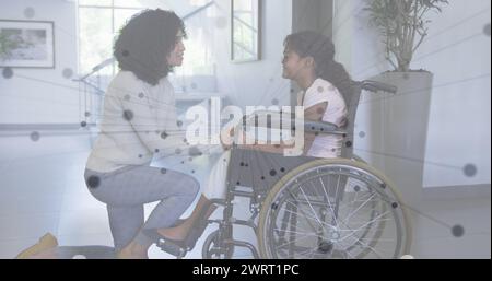 Image d'un réseau de connexions sur une mère afro-américaine et sa fille en fauteuil roulant Banque D'Images
