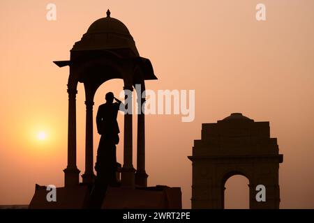 Silhouette de Subhas Chandra Bose statue sous la canopée derrière le monument commémoratif de guerre de la porte de l'Inde dans un coucher de soleil glorieux, statue monolithique Netaji en granit noir Banque D'Images
