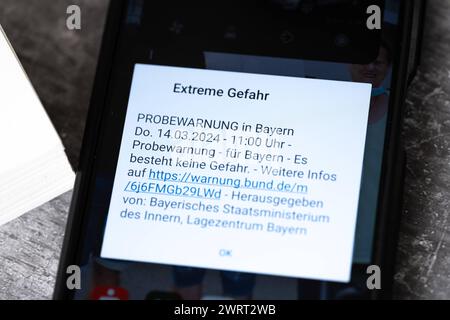 Langweid, Bavière, Allemagne - 14 mars 2024 : alarme de test d'image thématique le 14 mars à 11 heures en Bavière. Smartphone avec le message d'avertissement : danger extrême, sur l'écran *** Themenbild Probealarm AM 14 März um 11 Uhr dans le Bayern. Smartphone mit der Warnmeldung : Extreme Gefahr, auf dem Bildschirm Banque D'Images