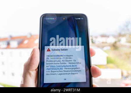 Langweid, Bavière, Allemagne - 14 mars 2024 : alarme de test d'image thématique le 14 mars à 11 heures en Bavière. Smartphone avec le message d'avertissement : danger extrême, sur l'écran *** Themenbild Probealarm AM 14 März um 11 Uhr dans le Bayern. Smartphone mit der Warnmeldung : Extreme Gefahr, auf dem Bildschirm Banque D'Images