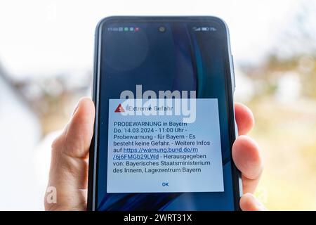 Langweid, Bavière, Allemagne - 14 mars 2024 : alarme de test d'image thématique le 14 mars à 11 heures en Bavière. Smartphone avec le message d'avertissement : danger extrême, sur l'écran *** Themenbild Probealarm AM 14 März um 11 Uhr dans le Bayern. Smartphone mit der Warnmeldung : Extreme Gefahr, auf dem Bildschirm Banque D'Images