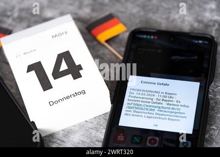 Langweid, Bavière, Allemagne - 14 mars 2024 : alarme de test d'image thématique le 14 mars à 11 heures en Bavière. Smartphone avec le message d'avertissement : danger extrême, sur l'écran *** Themenbild Probealarm AM 14 März um 11 Uhr dans le Bayern. Smartphone mit der Warnmeldung : Extreme Gefahr, auf dem Bildschirm Banque D'Images