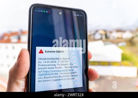 Langweid, Bavière, Allemagne - 14 mars 2024 : alarme de test d'image thématique le 14 mars à 11 heures en Bavière. Smartphone avec le message d'avertissement : danger extrême, sur l'écran *** Themenbild Probealarm AM 14 März um 11 Uhr dans le Bayern. Smartphone mit der Warnmeldung : Extreme Gefahr, auf dem Bildschirm Banque D'Images