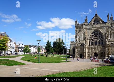 Vue de la cathédrale (église de la cathédrale Saint-Pierre dans l'Essex) avec place de la cathédrale à l'arrière et les touristes appréciant le soleil, Exeter, Royaume-Uni. Banque D'Images