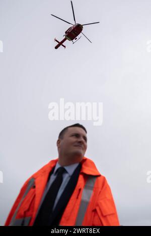 Le secrétaire à la santé de l'ombre, Wes Streeting, regarde l'hélicoptère décoller lors d'une visite à London Air Ambulance, au Royal London Hospital. Date de la photo : jeudi 14 mars 2024. Banque D'Images