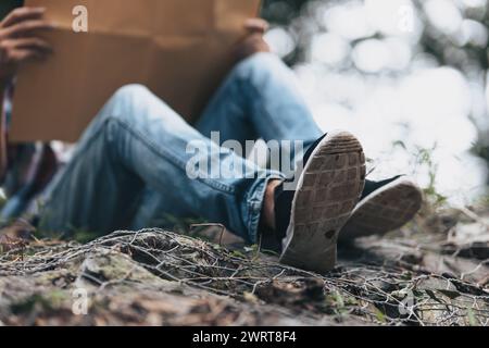 Randonneur perdu avec sac à dos assis près de la rivière et vérifie la carte pour trouver des directions dans la forêt. concept de randonnée et d'aventure. Banque D'Images
