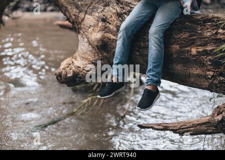 Randonneur perdu avec sac à dos assis près de la rivière et vérifie la carte pour trouver des directions dans la forêt. concept de randonnée et d'aventure. Banque D'Images
