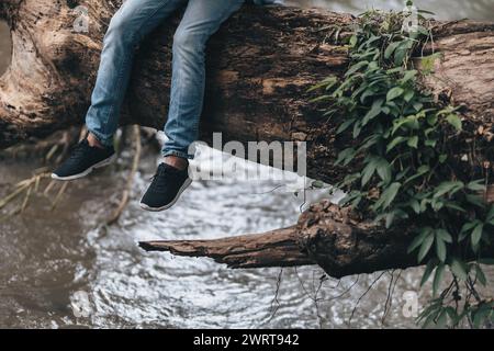 Randonneur perdu avec sac à dos assis près de la rivière et vérifie la carte pour trouver des directions dans la forêt. concept de randonnée et d'aventure. Banque D'Images