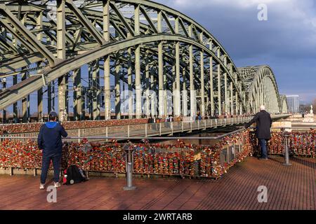 Deux hommes debout à la clôture avec les écluses d'amour au pont Hohenzollern, Cologne, Allemagne. zwei Maenner stehen am Zaun mit den Liebesschloessern an d. Banque D'Images