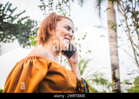 Une femme passe un coup de fil dans un jardin botanique. Banque D'Images