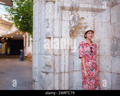 Voyage d'été féminin à Antalya, Turquie. Jeune femme asiatique en robe rouge marcher à travers la vieille ville Kalechi , voyageur touristique féminin découvrir des endroits intéressants et attraction touristique populaire Banque D'Images