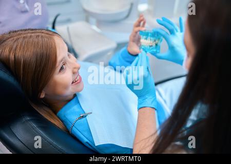 Une femme tient un modèle de dentition dans ses mains Banque D'Images